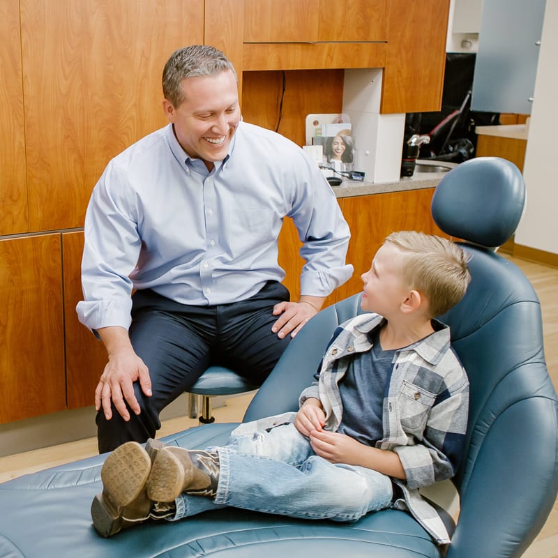 Dr. Jared Cox smiles at a young patient in a dental chair 